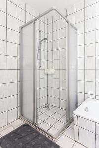 La salle de bains est pourvue d'une douche avec une porte en verre. dans l'établissement Ferienwohnungen im Haus Eversmeer, à Eversmeer