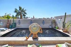 una persona con un cappello di paglia in piedi accanto alla piscina di Dar Kandi a Marrakech