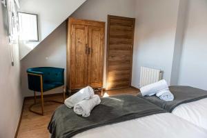 1 dormitorio con 2 camas y silla azul en Casa Rural Valsain Lodge, en La Pradera de Navalhorno