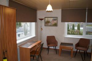 ein Wartezimmer mit Stühlen, einem Schreibtisch und 2 Fenstern in der Unterkunft Nooruse Majutus in Kuressaare