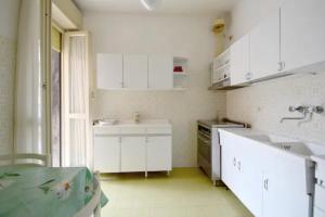 Una cocina blanca con gabinetes blancos y un fregadero. en Trilocale con posto auto privato a 5 minuti a piedi dalla spiaggia, en Rapallo