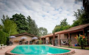 einen Pool vor einem Haus mit Tischen und Stühlen in der Unterkunft Mont Blanc in Villa General Belgrano
