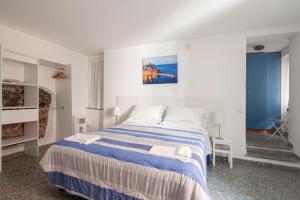 a white bedroom with a blue and white bed at Ludovica Flat in Vernazza