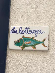 un cartello con un pesce sul lato di un muro di La Bottarga a Favignana
