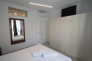 a white bedroom with a bed and a mirror at Appartamento piazza Buccelli a 10 mt dal mare in Varazze