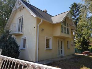 a small yellow house with a porch and a balcony at Tóparti Vendégház - Lipót, Magyarország in Lipót