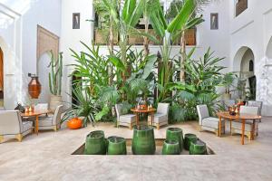 un patio con mesas, sillas y plantas en Dar Kandi en Marrakech