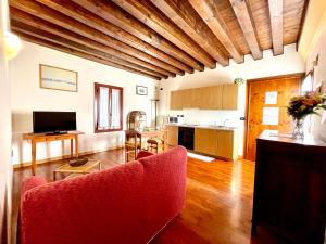 a living room with a red couch and a kitchen at Alla Barchessa di Villa Querini in Preganziol