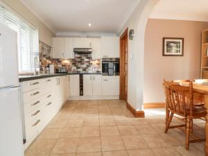 a kitchen with white cabinets and a table at Hazel Cottage in Tintagel