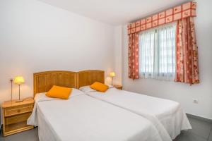 2 łóżka w sypialni z białą pościelą i pomarańczowymi poduszkami w obiekcie Apartamentos Hipocampos Unitursa w mieście Calpe