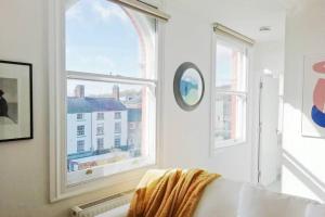 a white room with two windows and a couch at Cosy, elegant apartment in heart of Ludlow Town in Ludlow