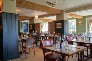 a restaurant with wooden tables and chairs with wine glasses at Beckford Inn in Beckford