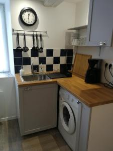 a kitchen with a washing machine and a clock on the wall at La maison du Sotré in Raon-sur-Plaine