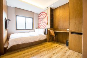 1 dormitorio con cama, ventana y escritorio en Easylazy Inn, en Taichung