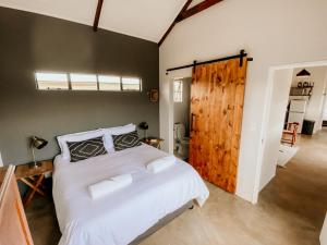 a bedroom with a white bed and a wooden door at Kezlyn Farm Cottages in Bergville