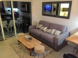 キャヴァレール・シュル・メールにあるModerne T2 avec garage ,très calme avec jardin privé et piscine, à 400m du centre ville et des plages, WIFI remise supplémentaire de 10 pourcent pour une location à la semaineのソファとテーブルのあるリビングルーム