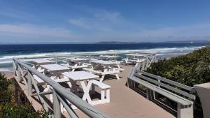una fila de mesas y bancos en la playa en The Dunes Villa 11, en Plettenberg Bay