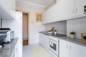 una cocina blanca con armarios y electrodomésticos blancos en Spacious Comfortable Apartment - Balcony en Oporto