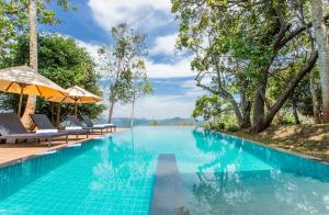 una piscina en un complejo con sillas y sombrillas en Mountbatten Bungalow- Thema Collection en Kandy