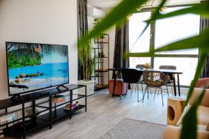 sala de estar con TV de pantalla plana y mesa en Onix 75, en Mamaia Nord – Năvodari