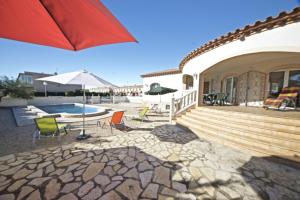 a patio with chairs and an umbrella and a pool at Villa Nicole in L'Ampolla
