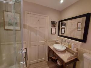 a bathroom with a sink and a shower with a mirror at Rectory Farm Annexe in Counthorpe