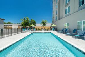 une piscine avec des chaises et un bâtiment dans l'établissement La Quinta by Wyndham Mobile, à Mobile