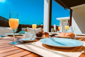 a wooden table with plates of food and glasses of orange juice at Chania Paradise Retreat - Falasarna Villa Nostalgia in Plátanos