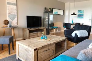 uma sala de estar com uma televisão, um sofá e uma mesa em fewo1846 - FoerdeNest - familienfreundliche Wohnung mit 2 Balkonen und Meerblick em Harrislee