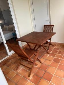 a wooden table and two chairs in a room at RÉSIDENCE DE LA BAIE Sunshine TARTANE in La Trinité