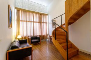 a living room with a staircase and a chair at Grande Hotel de Ouro Preto - 80 ANOS in Ouro Preto