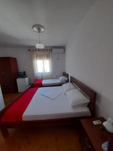 a bedroom with two beds with red and white sheets at B&BSheshalliu in Berat