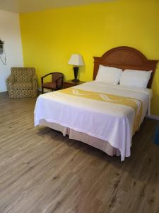 a bedroom with a large bed and a yellow wall at Sunset Motel Santa Rosa, NM in Santa Rosa
