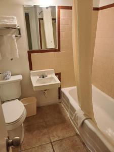 a bathroom with a toilet and a sink and a tub at Sunset Motel Santa Rosa, NM in Santa Rosa