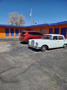 two cars parked in a parking lot in front of a building at Sunset Motel Santa Rosa, NM in Santa Rosa +2 photos