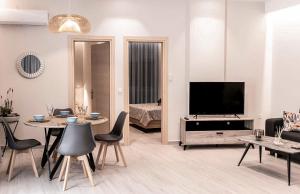 un soggiorno con TV, tavolo e sedie di "NISSI BEACH" Houses a Città di Kos