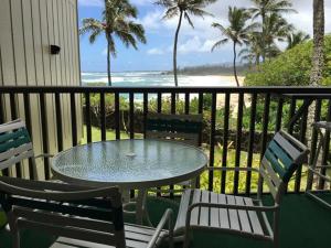 una mesa y sillas en un balcón con vistas a la playa en Wailua Bay View Resort en Kapaa