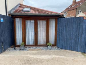 a house with a wooden door and a fence at The little crab hut in Sheringham