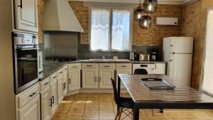una cucina con armadi bianchi e un tavolo di Grand Gite La Salamandre Proche Sarlat de 1 à 10 personnes a Saint-André-dʼAllas