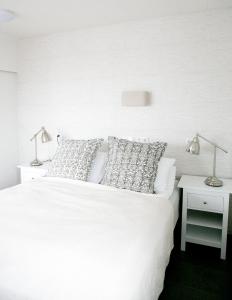 uma cama branca com duas lâmpadas numa mesa lateral em Cave apartment em Þórshöfn