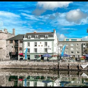 a white building with blue umbrellas next to a body of water at The Three Crowns B&B in Plymouth