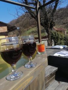 dois copos de vinho sentados numa mesa de madeira em Casa De Vacanta Silvia Varmaga em Vărmaga