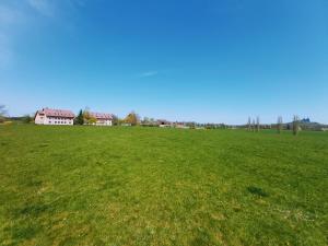 a large field of green grass with houses in the background at Resort Český ráj in Troskovice