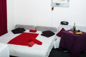 Una cama con almohadas rojas y negras y una mesa. en Wellness Želešice, en Želešice
