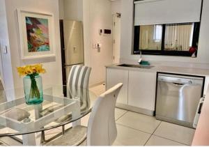 a kitchen with a glass table with a vase of flowers at One Hyde Park Sandton in Johannesburg