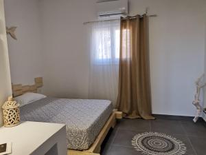 a small bedroom with a bed and a window at Family Villages Santorini in Vlychada Beach