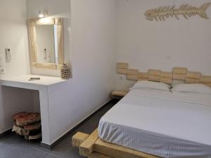 a white bedroom with a bed and a mirror at Family Villages Santorini in Vlychada Beach