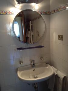 ein weißes Badezimmer mit einem Waschbecken und einem Spiegel in der Unterkunft Garni Hofer in Sexten
