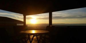 a table and chairs on a balcony with the sunset at B&B Bella Vista in Dorgali