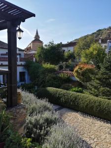 a garden with bushes and a pathway with a building at Casona Del Duende in Alájar